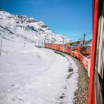 treno rosso della ferrovia retica immerso in un panorama innevato